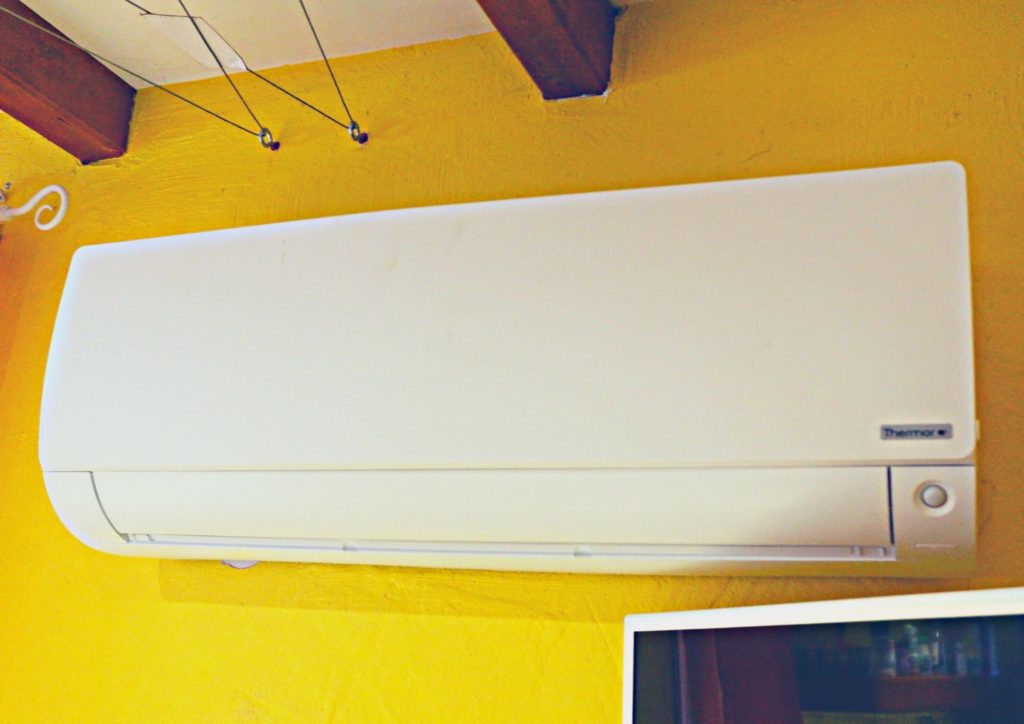une unité climatisation intérieure blanche sur un mur de couleur jaune canarie