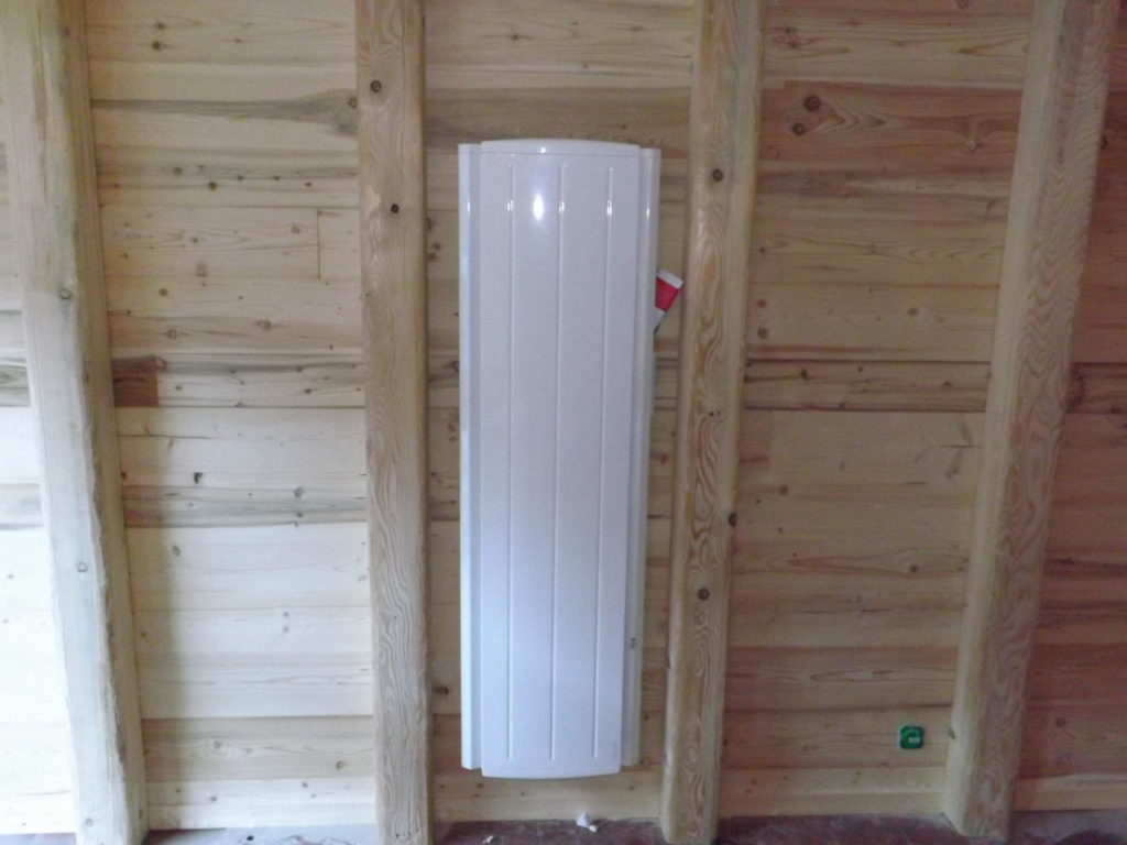 Un chauffage vertical blanc sur un mur en bois