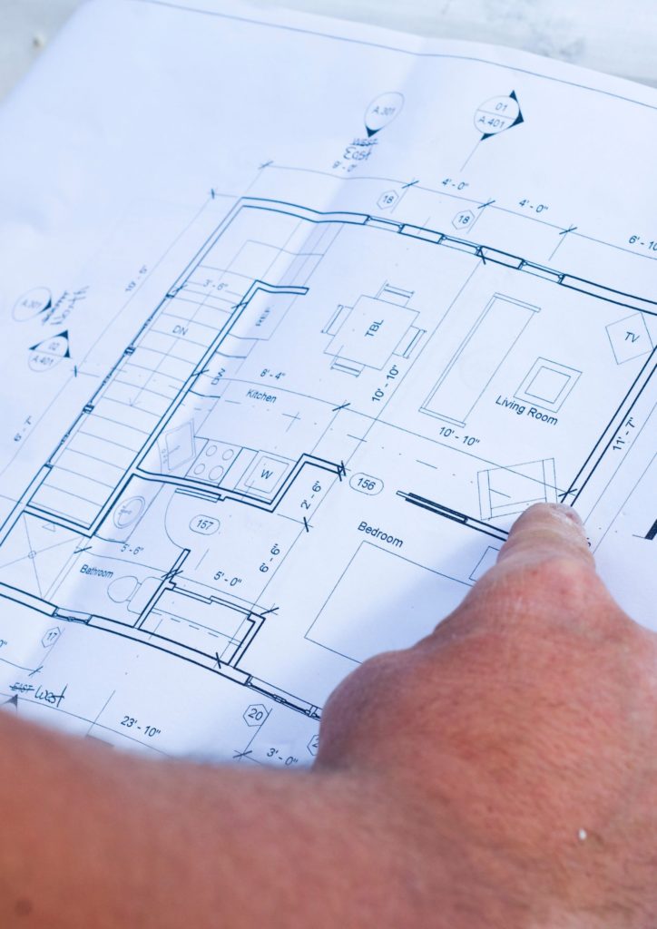 Plan d'une habitation avec une main qui montre des éléments dessus