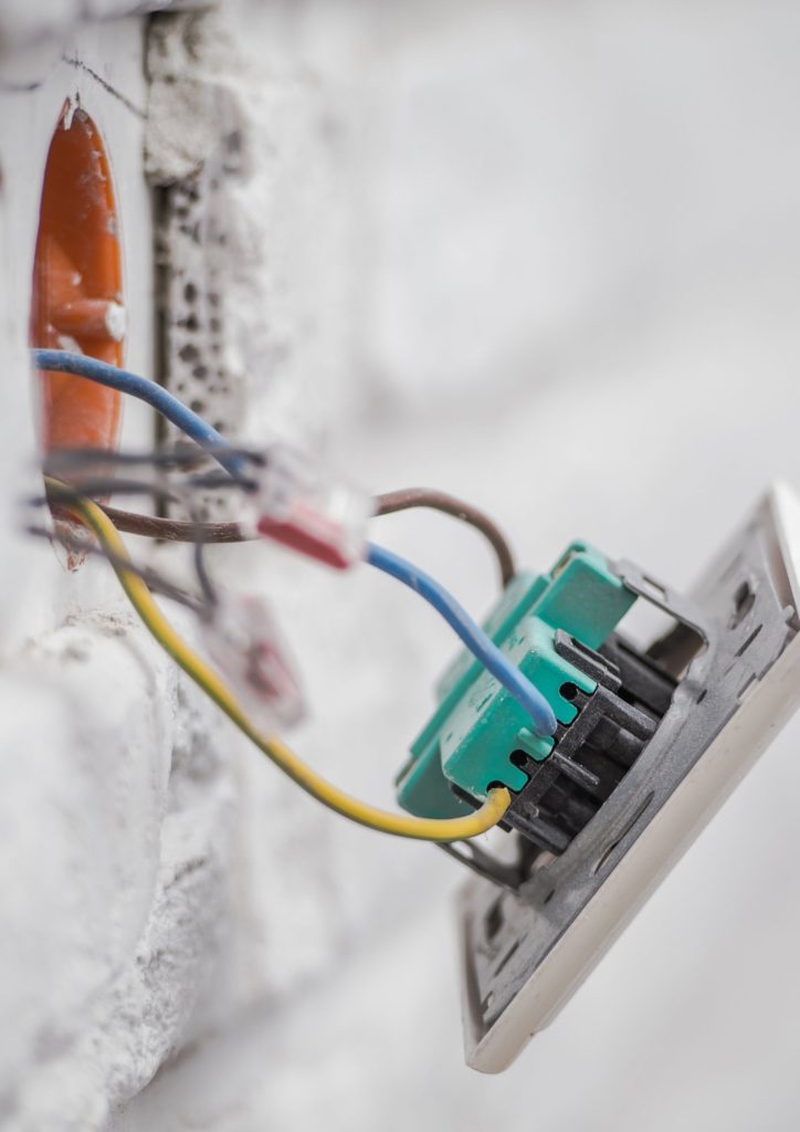 Une prise encastrée qui sort du mur et qui tien par les fils électriques.